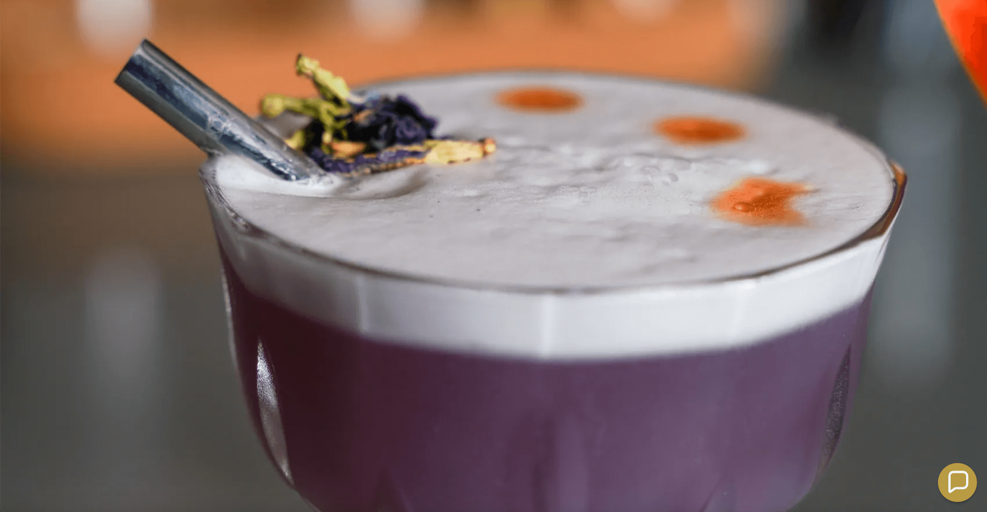 Purple cocktail with black metal straw and dried butterfly pea flowers garnish, showcasing Ecolux's Sipper Collection